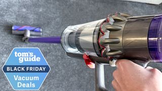 Dyson V11 Advanced cordless vacuum in the hand with a Tom&#039;s Guide deal badge attached