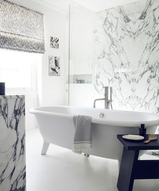 An example of bathroom pictures showing a white bath in the center of a marble bathroom with a glass shower wall