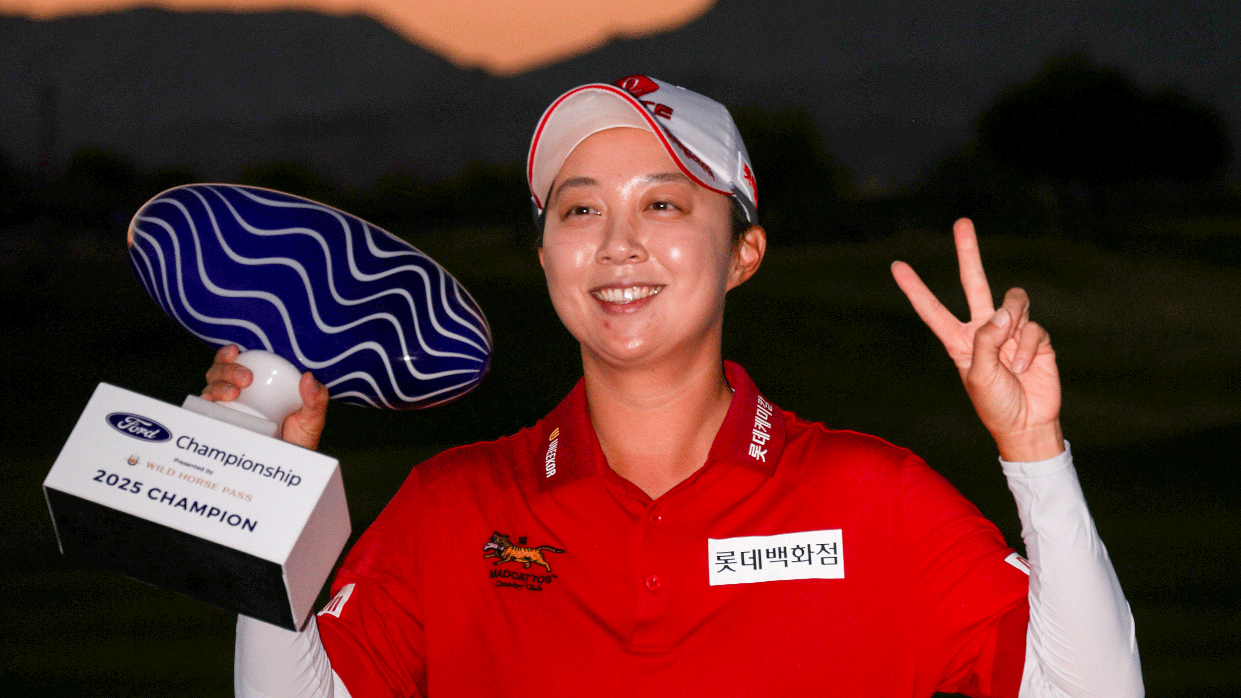 Hyo Joo Kim holds up the Ford Championship trophy and throws a peace sign after winning in 2025