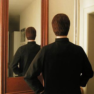 Man with head covered in hair looking in the mirror