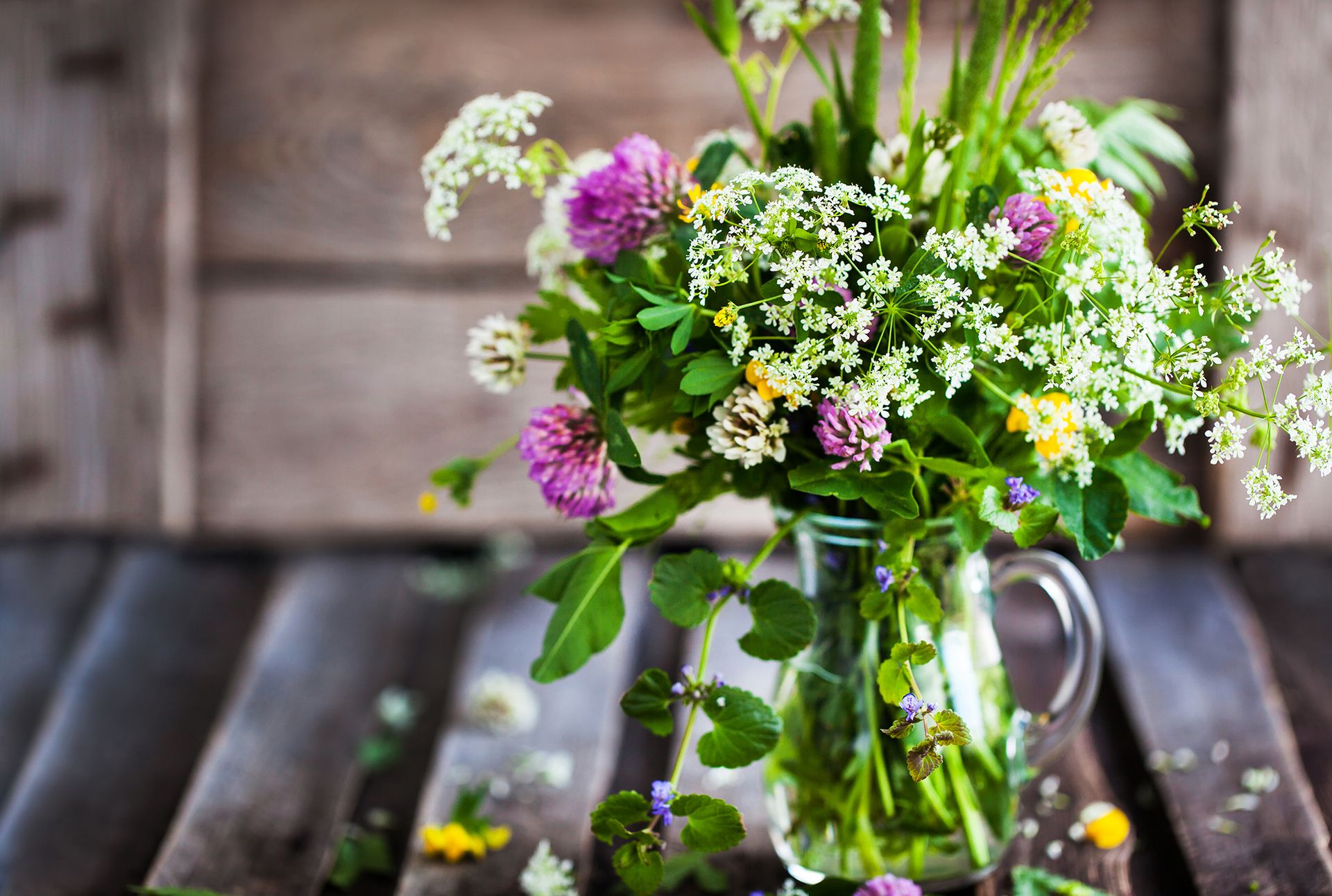 Bouquet of wildflowers in glass jar on wooden table