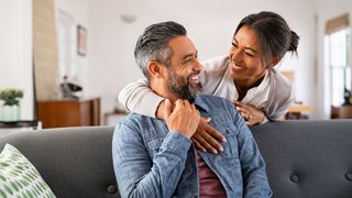 Couple laughing sitting on the sofa together and talking, representing how to have better sex