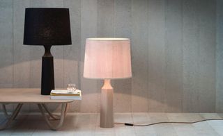 'Derome' table lamps by Pinch. A black lamp on a wooden table and a pink lamp next to it on a wooden floor.