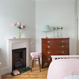 white bedroom with wooden flooring with bedside fire place