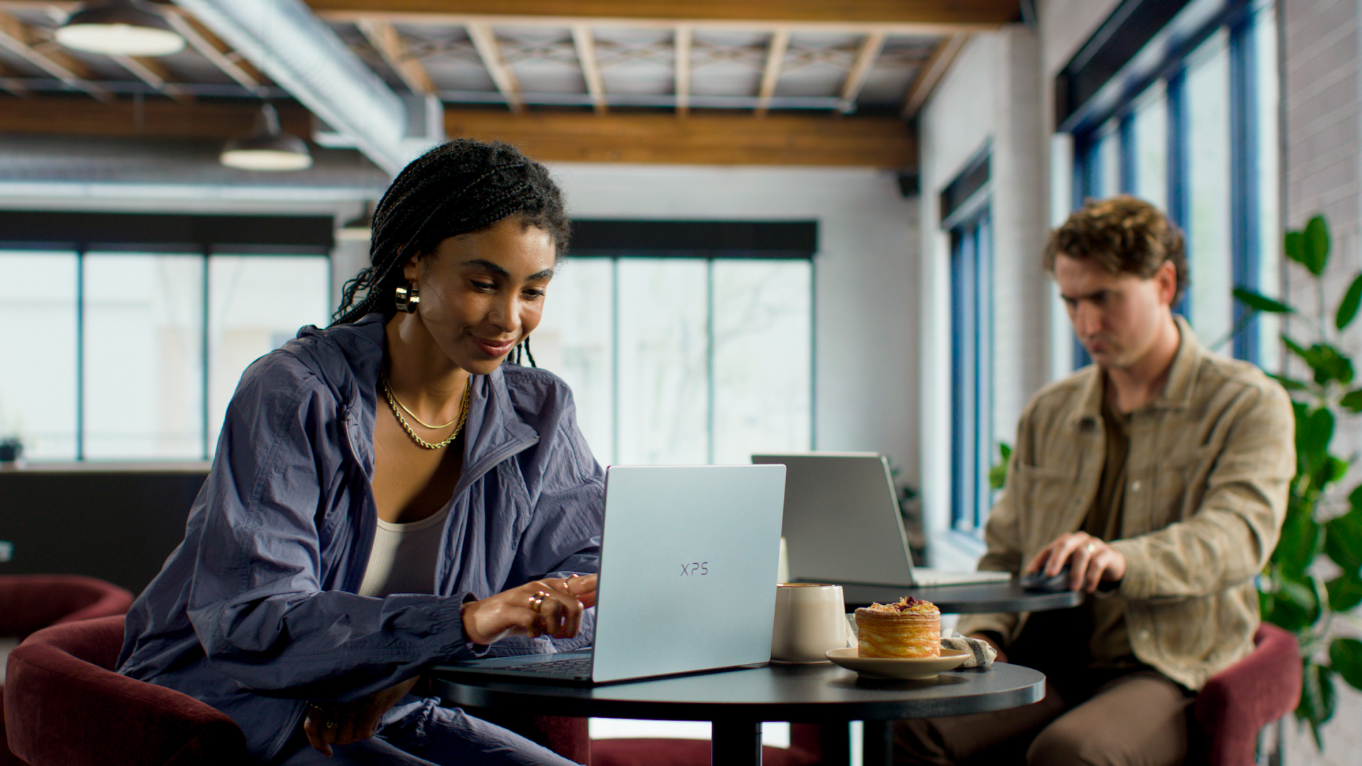Dell XPS 13 being used by a person in a cafe, on a table next to a cake