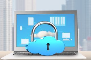 Cloud padlock resting on laptop with city skyline behind