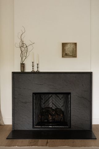 A living room fireplace with undersized wall art and candles