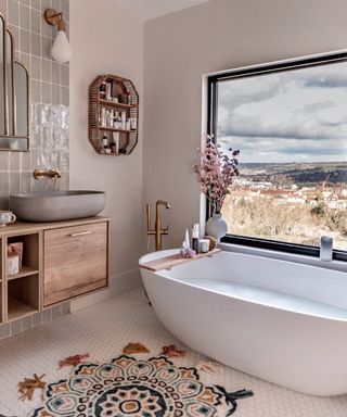 A bathroom idea with white freestanding bath, grey concrete basin, wooden vanity and Mandala shaped rug