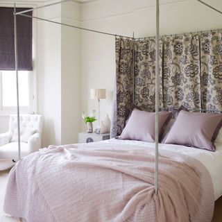 summer bedroom with four poster bed and floral bed curtains throws and cushions