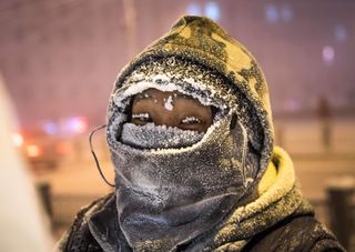 Headshot of an artist wrapped up with ice on their clothes and eyelashes