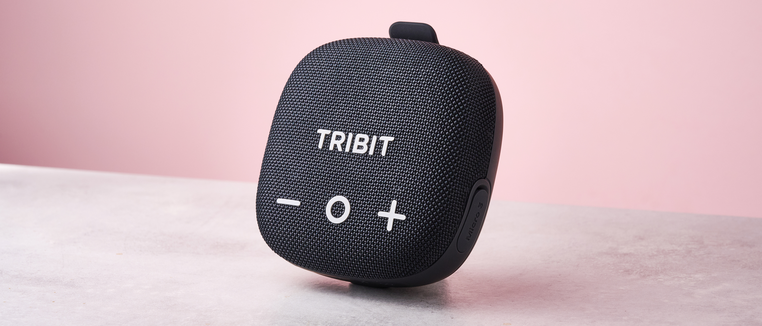 The Tribit Stormbox Micro 3 standing in front of a pink background.