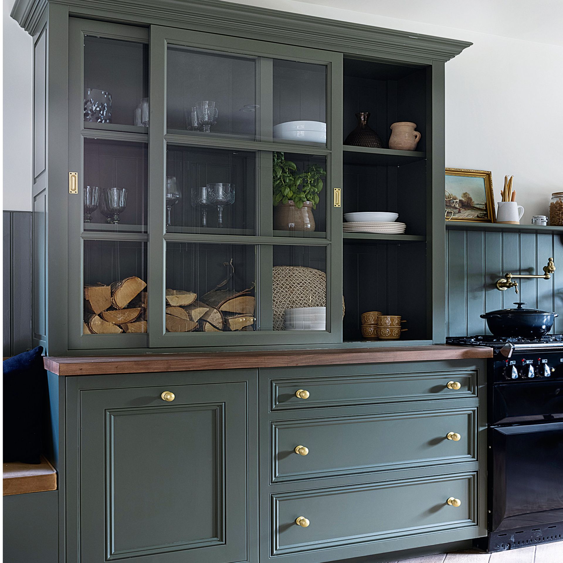 green cabinets with glass windows containing glasses, bowls and wood
