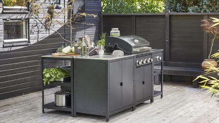 An Ikea GRILLSKÄR charcoal barbecue grill in black/stainless steel on outdoor deck in backyard exterior setting