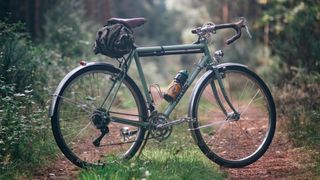 A green classic touring bike on a woodland path