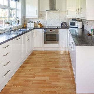 white kitchen with wooden flooring and chimney stack