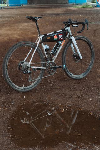 A three quarter view of a white gravel bike in front of a puddle