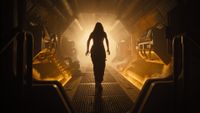 woman stands in the centre of the frame, silhoutetted against a light background