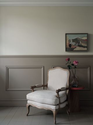 living room with floor and paneling painted the same color, armchair, side table, artwork, cream wall