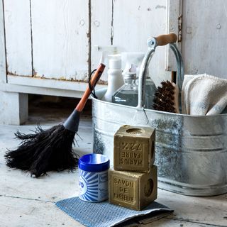 Galvanised steel caddy with cleaning products inside on a wood floor