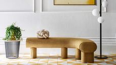 Yellow and white tile floor, yellow curved bench, white walls