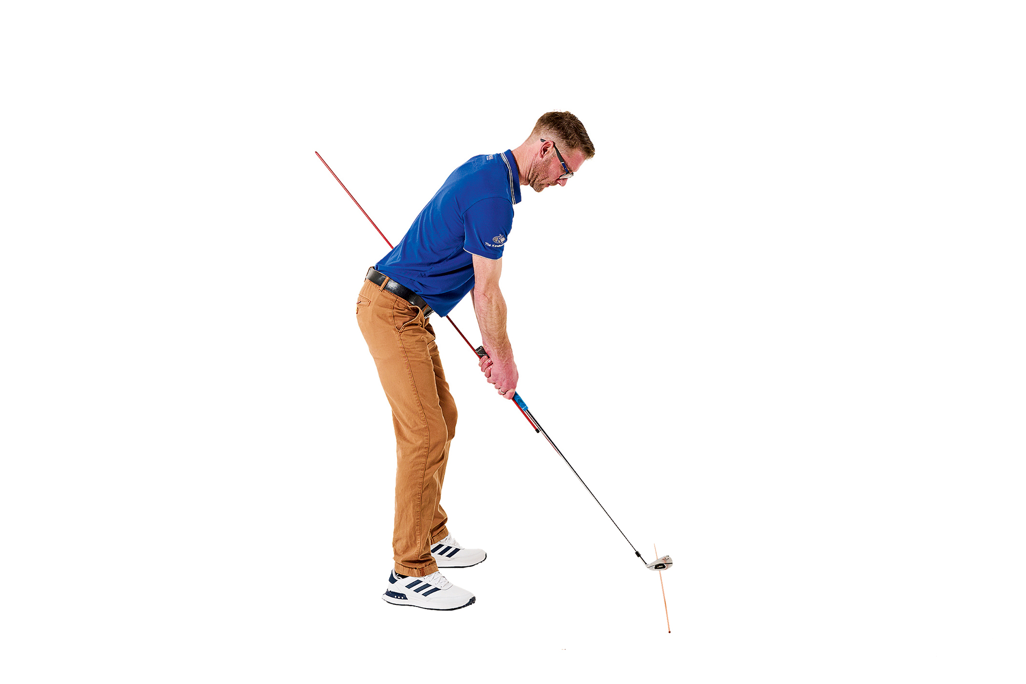 Tom Motley demonstrating the golf swing plane mirror drill at address, with an alignment stick gripped next to the golf club pointing back past the lead hip