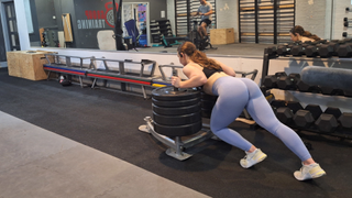 Woman doing sled push in gym