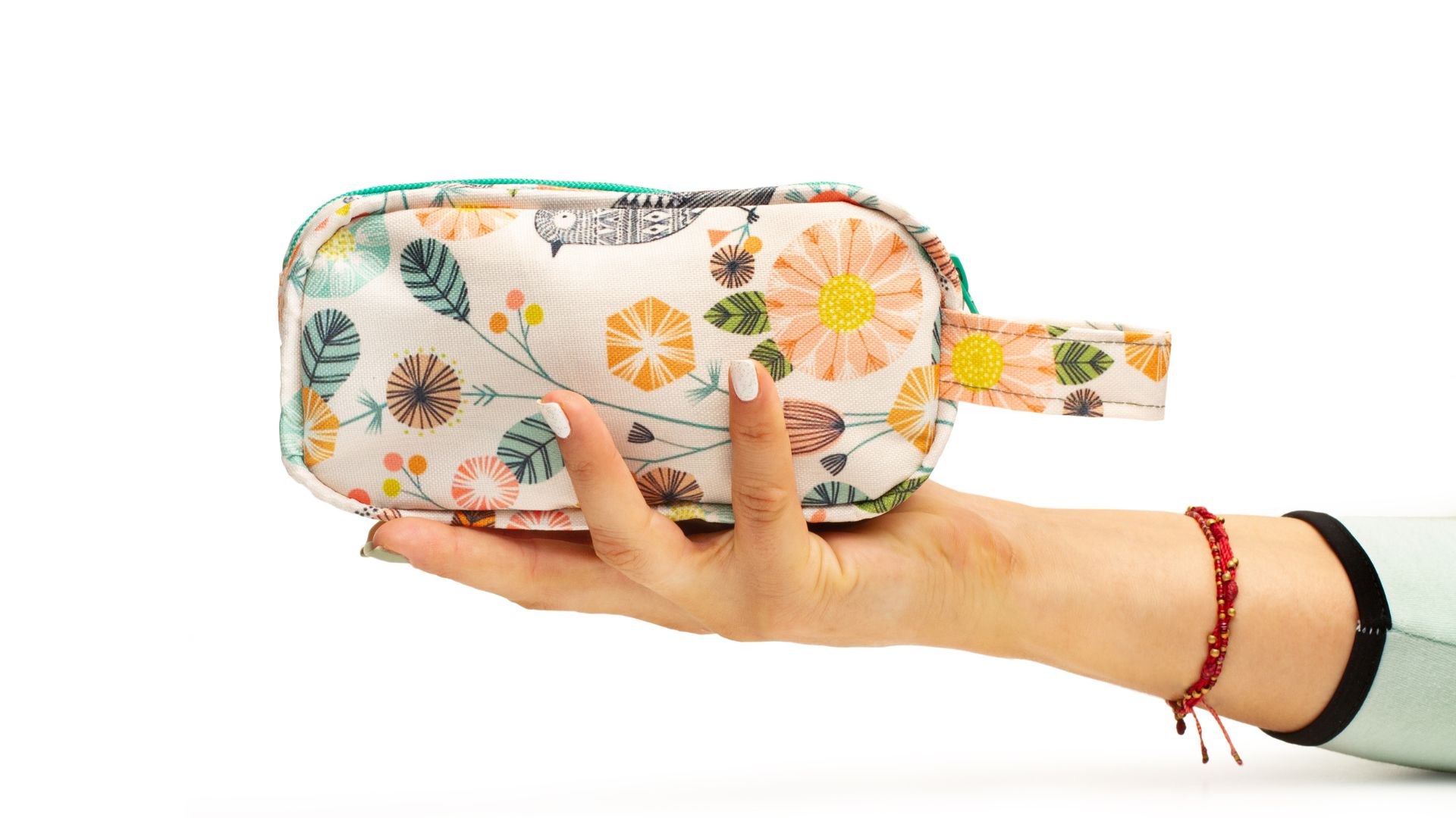 A woman's manicured hand holds a toiletry bag with a cute floral design.