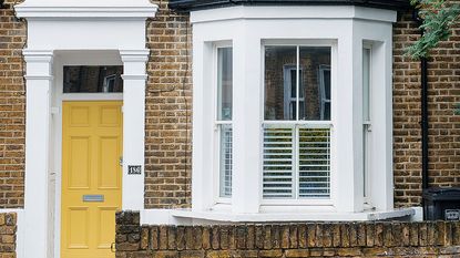 house exterior with yellow front door and bay window