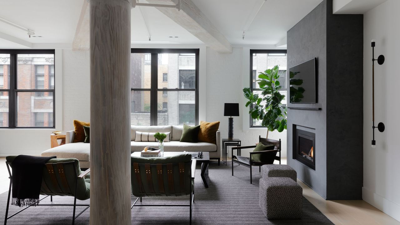 NYC loft apartment living room with timber columns and black-framed windows and a fireplace