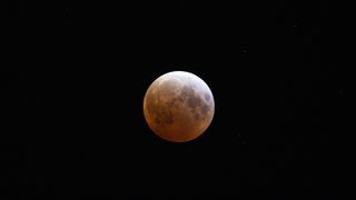 red moon during total lunar eclipse with a pale white upper right corner.