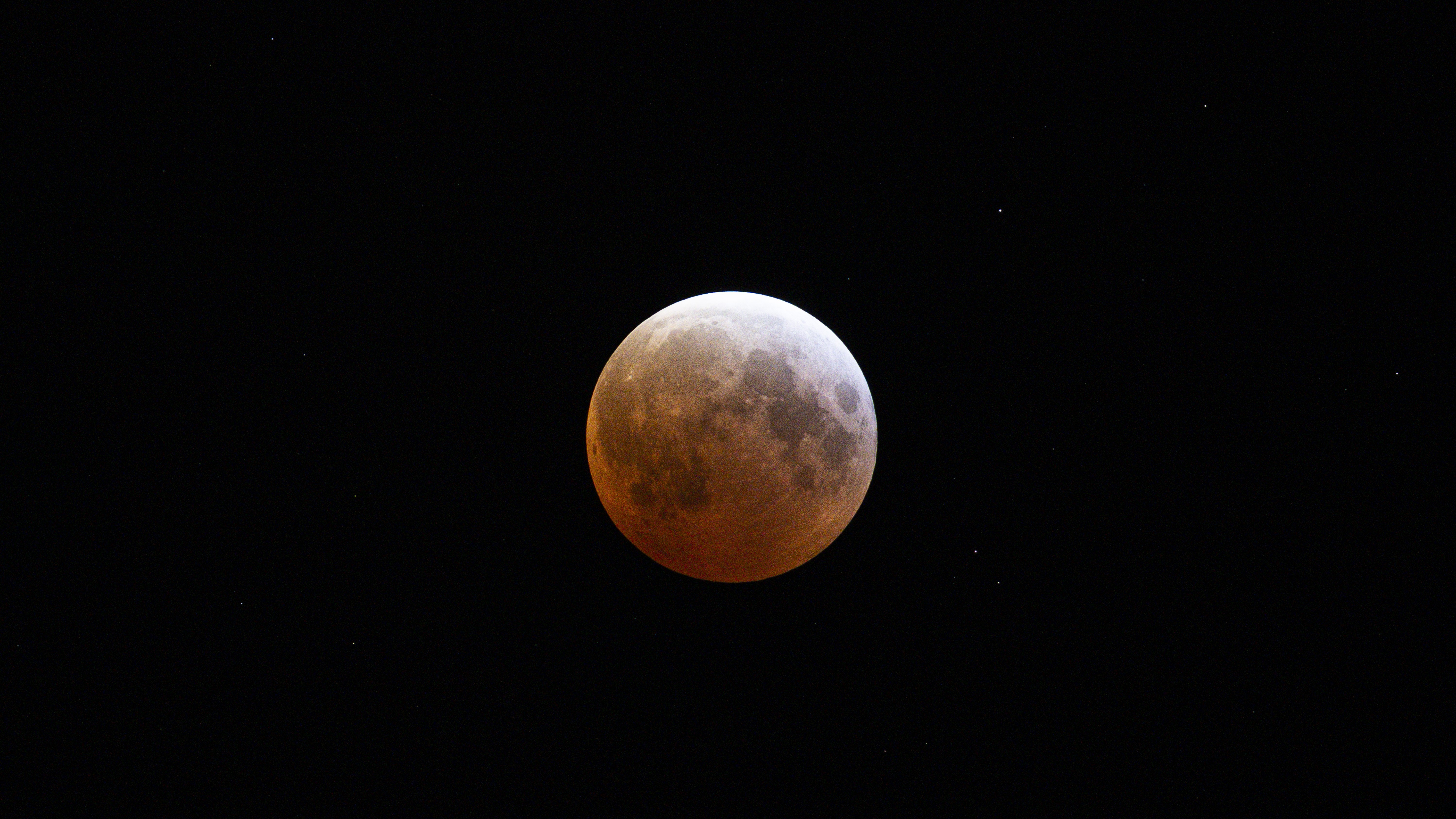 red moon during total lunar eclipse with a pale white upper right corner.