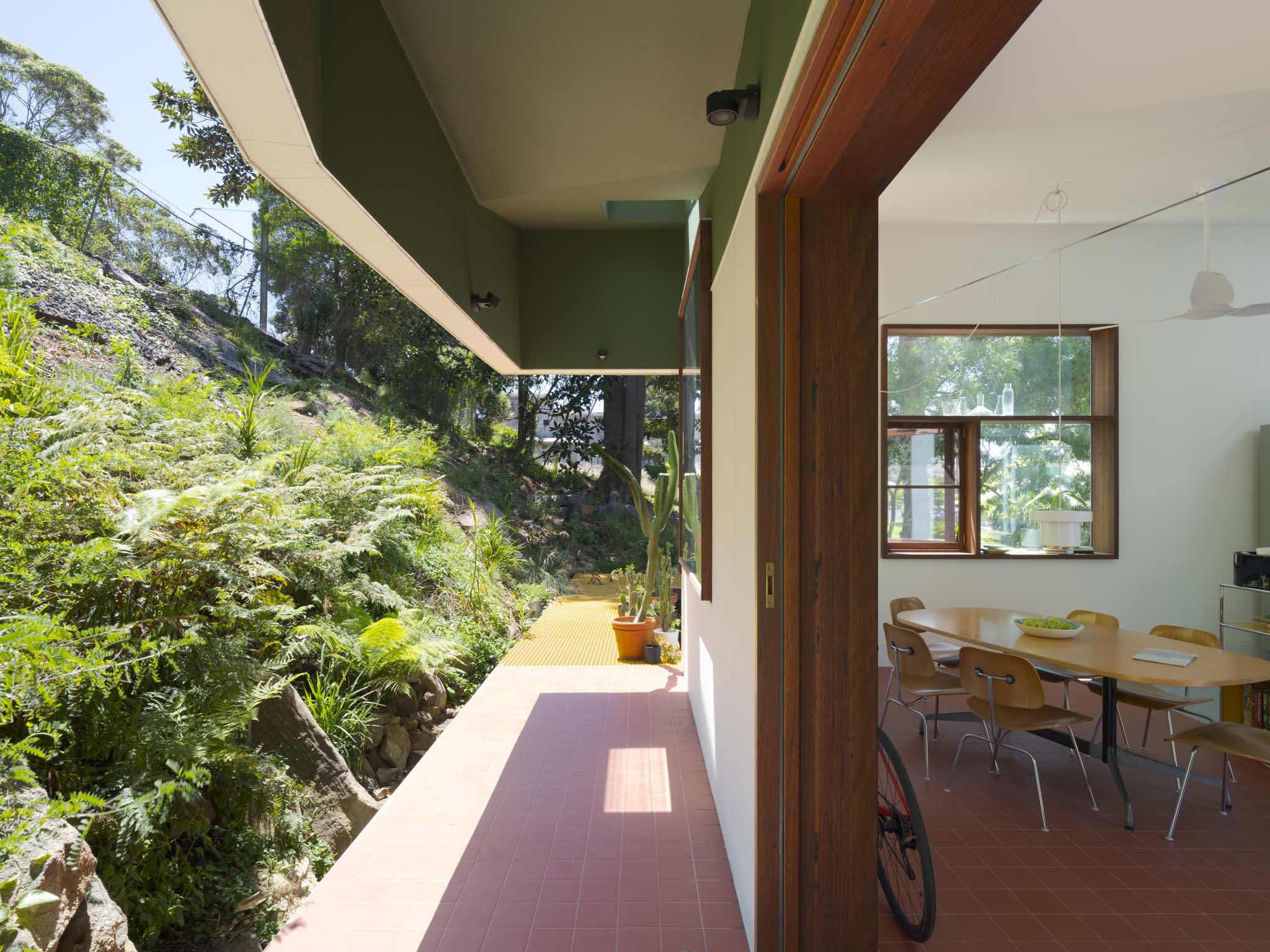a white boxy house, scarborough house in australia, among wooded setting and with colourful furniture