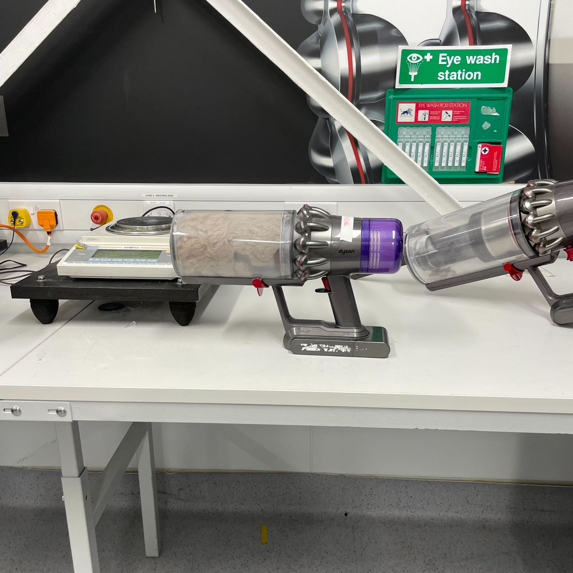 Dyson lab with a vacuum sitting on a desk that has a filled dust canister