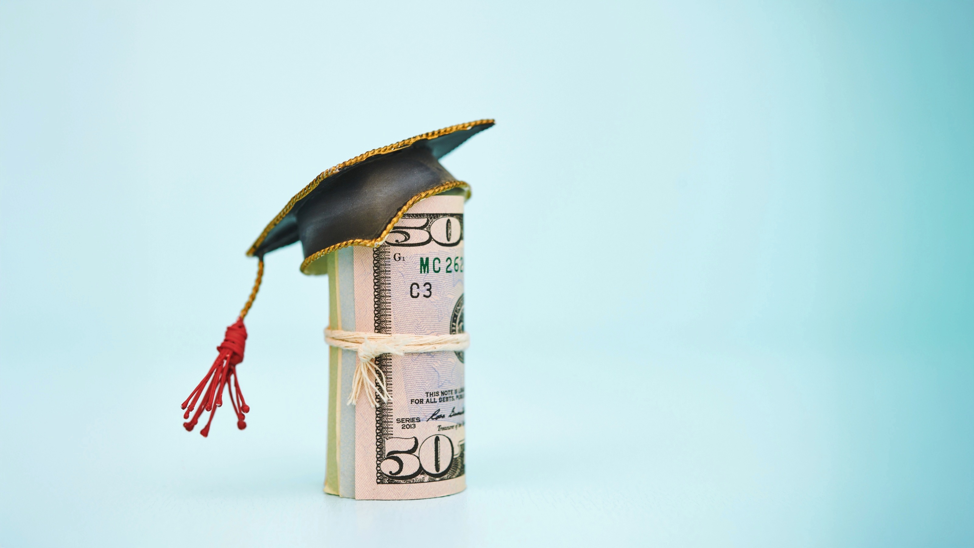 Money roll wearing a mortarboard graduation cap