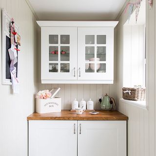 utility room with white wall and cupboard with wooden platform