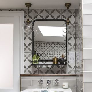 Bathroom in loft extension, wooden floor, shower cubicle with glossy grey wall tiles, grey vanity unit and glass pendant lights in front of black wall mirror.