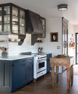 kitchen with dark navy cabinets, antique wooden butcher's block, white range and wooden floor