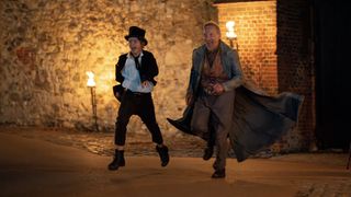 Billy Jenkins as Dodger and Christopher Eccleston as Fagin run through a street with grins on their faces in Dodger.