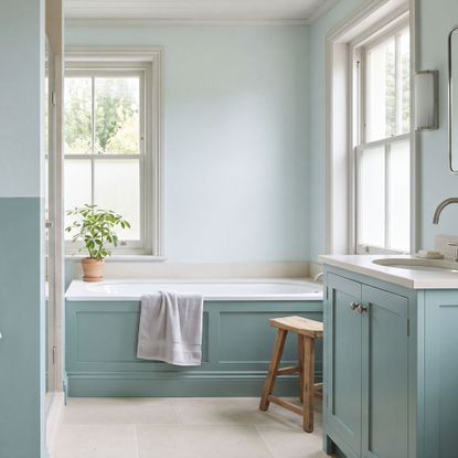 Bathroom with bath and lower half of walls painted aquamarine, and the top half a paler version