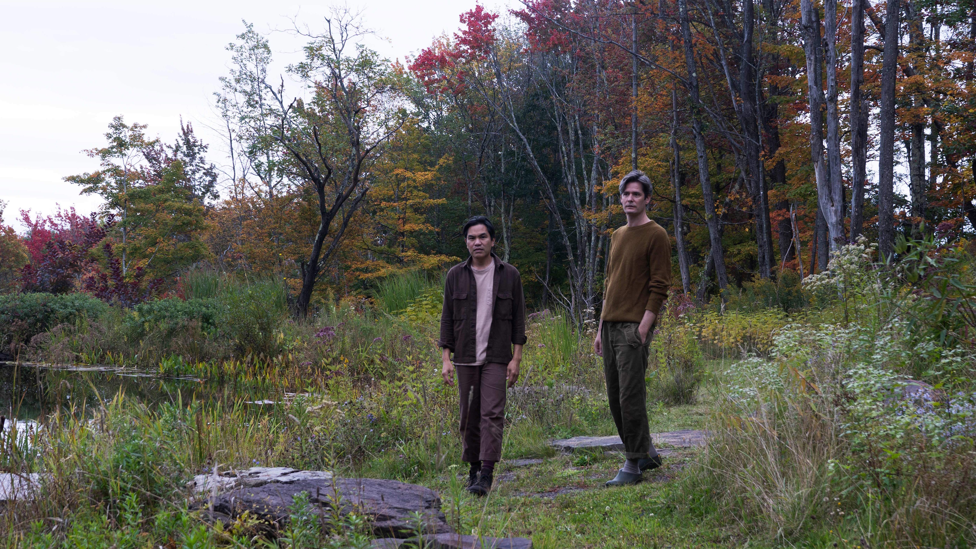 Alan Calpe and Christopher Crawford in their Catskills garden with a pond garden and trees and shrubs in fall