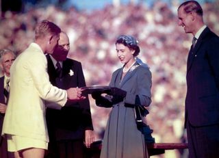 Queen Elizabeth II presents the Silver Salver to Australian tennis champion Lewis Hoad (1934 - 1994) at Centre Court, Kooyong, during her trip to Australia, 1954. Prince Philip stands nearby.