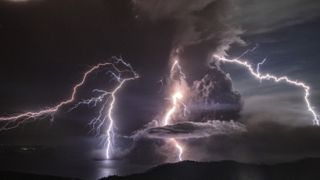 A column of ash surrounds the crater of Taal Volcano as it erupts on Jan. 12, 2020, with lightning in the background, as seen from Tagaytay city, in the Philippines. 