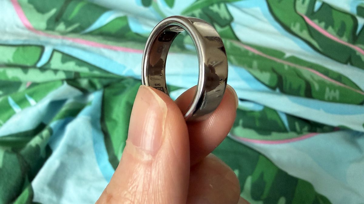 A close up of fingers holding the Oura Ring 5 in silver