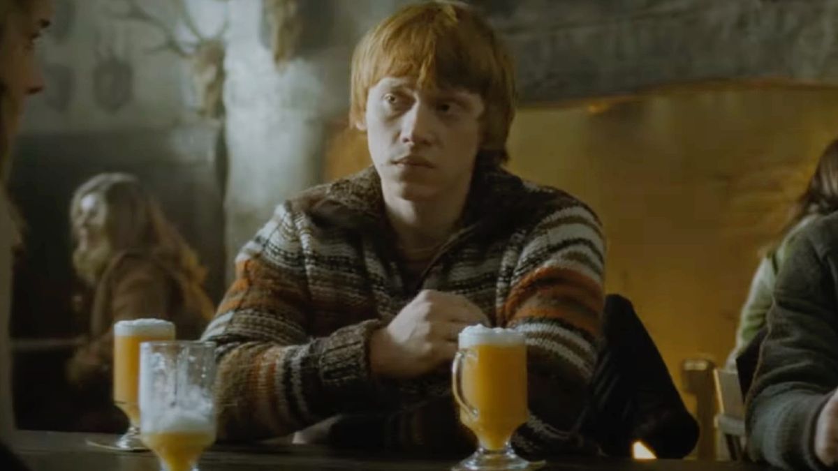 Ron Weasley looking at Hermione with a butterbeer close by