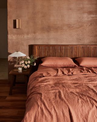 A bedroom with earthy walls, an orange bedding