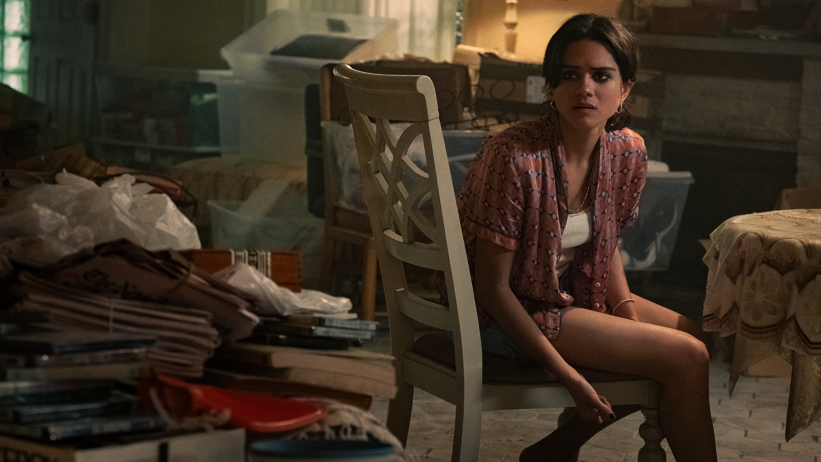 Sasha Calle's Desi looking behind herself while handcuffed to and seated on a chair in The RIP