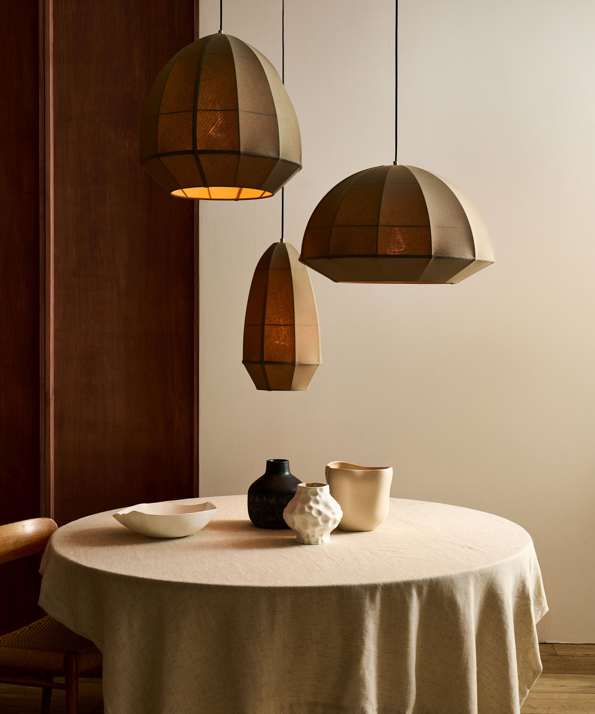 dark stone coloured trio of fabric sculptural pendant lights above small round table with cream cloth