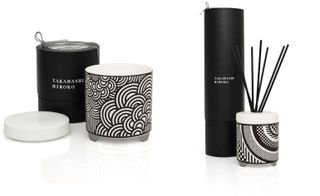 A candle in a black and white jar with fan design, alongside a reed diffuser with geometric design