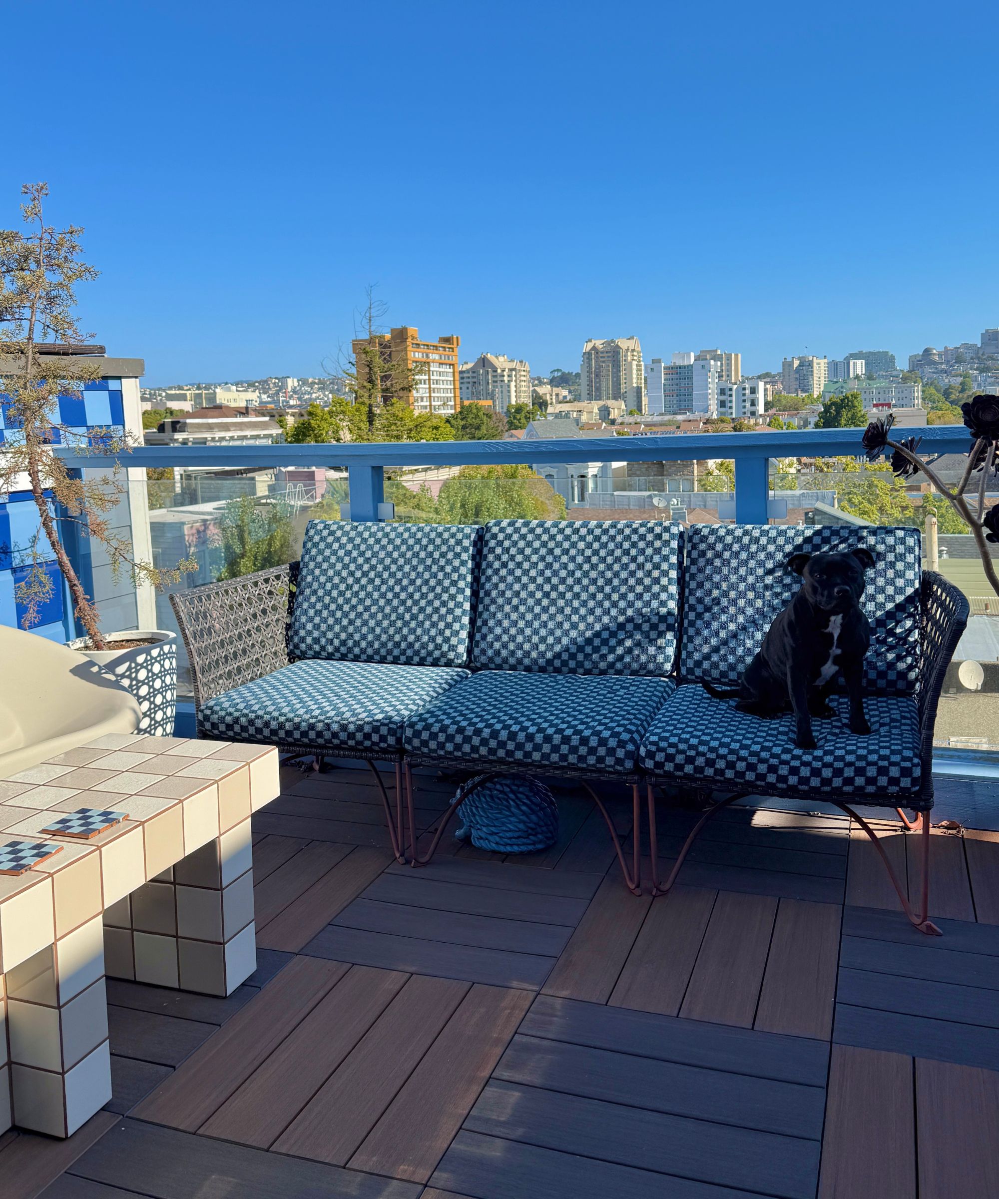 Balcony with rattan bench with checkerboard print cushions and coffee table