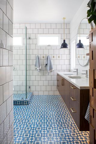 white bathroom with metro tiles, blue patterned floor tiles, walk in shower, walnut wall hung vanity unit